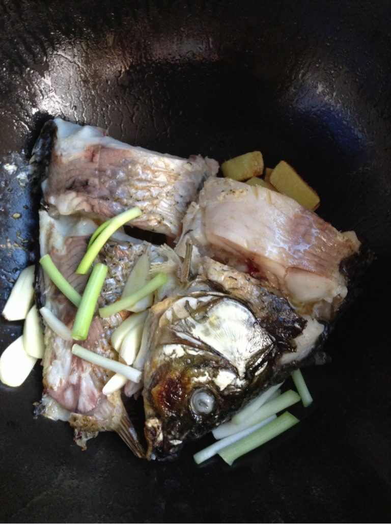 酱炖鲤鱼,2分钟后轻轻把鱼翻另一面，加葱段，蒜瓣，煎俩分钟