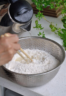 家常薄饼,面盆里倒入500g小麦面粉，倒入开水把1/2的面粉合成烫面碎