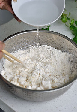 家常薄饼,用清水把剩余的面粉搅成面碎，把两种面揉和成一面团，倒少许花生油在手上