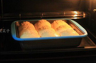 酸奶乳酪面包,预热烤箱，在面团表面刷上全蛋液、撒杏仁角，将面团放入烤箱中层或中下层，180度，上下火，18～20分钟