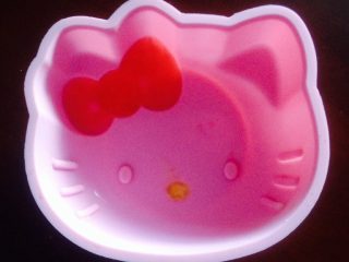 hello kitty酸奶慕斯蛋糕,把红色QQ糖融化倒至KT猫模具蝴蝶结位置，黄色QQ糖融化倒至嘴巴位置后放冰箱冷冻3分钟