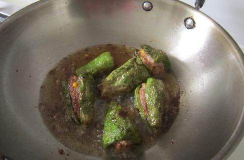 虎皮青椒酿肉,炸好的青椒捞起沥油，留少许油。重新开火，将青椒放入锅中