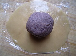 广式豆沙月饼,小球放在保鲜膜上，按成圆片，放上豆沙馅，收口，揉圆，外皮裹少许低粉