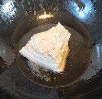 南乳扣肉,猪皮放入油锅，皮的一面面朝下炸，炸好后放入冷水中，浸泡十分钟
