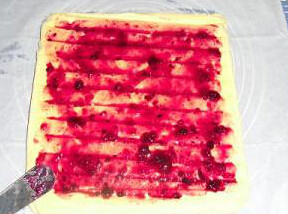 蓝莓椰丝蛋糕卷,稍冷放上一张干净的油纸倒过来，刷上一层蓝莓果酱