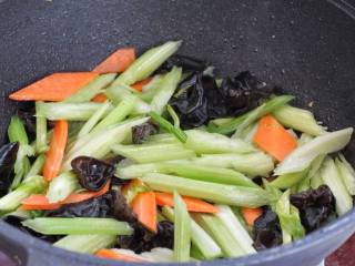 芹菜木耳炒肉丝,接着下入芹菜、木耳和胡萝卜，大火快速翻炒一分钟。