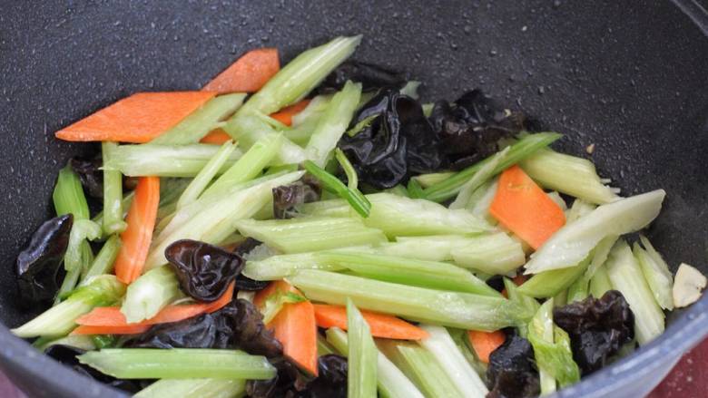 芹菜木耳炒肉丝,接着下入芹菜、木耳和胡萝卜，大火快速翻炒一分钟。