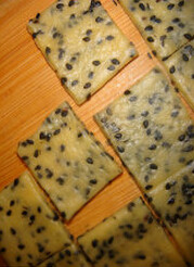黑芝麻咸香饼干,修整成长方形。切成小正方形。摆在烤盘上