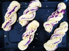 紫薯麻花面包,发至两倍大时，用刷子在表面刷一层蛋液，撒上奶酥粒