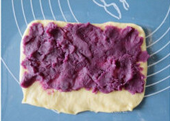 紫薯麻花面包,将面团擀成椭圆型，翻面，拉扯成长方形，铺上紫薯泥