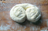 葱油手抓饼,将面片从上往下卷起来，从左右两端将面条卷起来，形成两个圈；