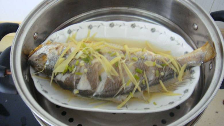 清蒸黄鱼,水开后加入大火蒸10分钟之后打开把鱼上的姜丝和葱花去掉，把盆内水倒掉