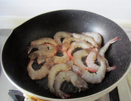 干烧基围虾,油锅烧热后煎虾至两面变色后转中小火，锅铲压虾头，煎出红油