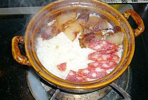 腊味煲仔饭 ,饭放入炉子上煲至只剩下一点点表面的水时放入腊肉、腊肠，小火再焖至表面基本看不到水