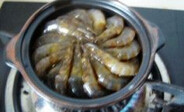 干锅基尾虾,将虾码到铺有生姜及大蒜的砂锅内