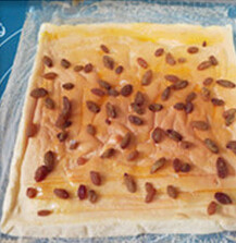 葡萄干瑞士卷,在蛋糕卷开始的地方用刀划三道痕印，抹上芒果果酱，撒上葡萄干