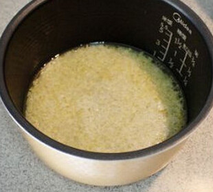 海南鸡饭,倒入电饭煲，再倒入适量的鸡汤，加少量的盐，开始煮饭