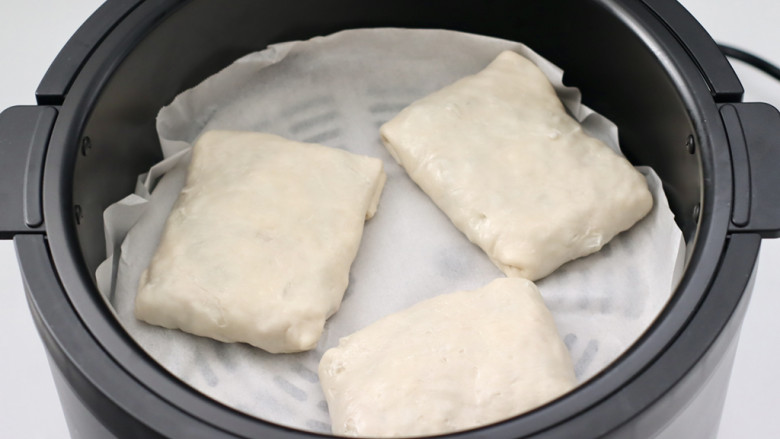 酸豆角烤包子,炸锅铺上油纸，放入包好的包子。