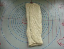 牛奶排包,取出翻面，压成大片，左右各向中间折叠一次