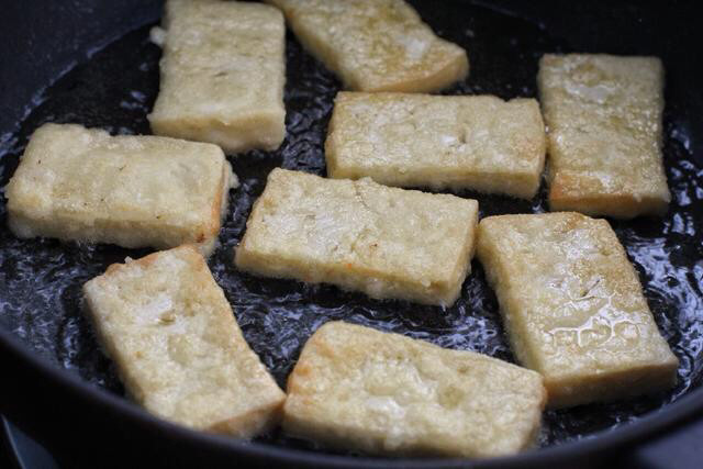 煎酿豆腐,锅中倒入比平时炒菜多一些的食用油，放入豆腐块用中小火煎至两面金黄色，用筷子夹出备用。