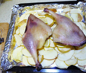 果香脆皮鸭,干瘪水果洗净切片平铺在铺了锡纸的烤盘上，柠檬切片垫在鸭腿下