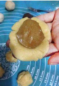 法式凤梨月饼,取一份面团摁扁成圆片，然后包裹上凤梨馅，收口放入模具里