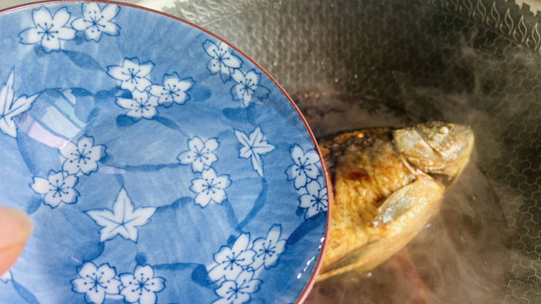 家常鲫鱼,加入一碗热水，盖上锅盖焖煮十分钟