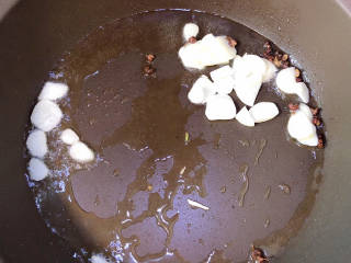 黄瓜烧豆腐,锅中倒入油，加热至五成热，放入花椒粒、蒜爆香。