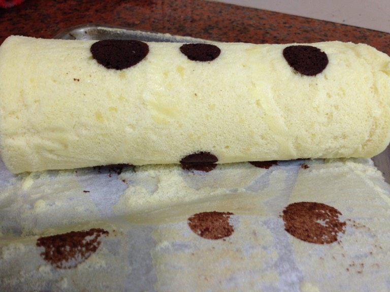 巧克力波点蛋糕卷,把蛋糕翻铺在烤架上，趁热去掉油纸，待蛋糕稍凉翻铺在油纸上利用油纸把它卷起来