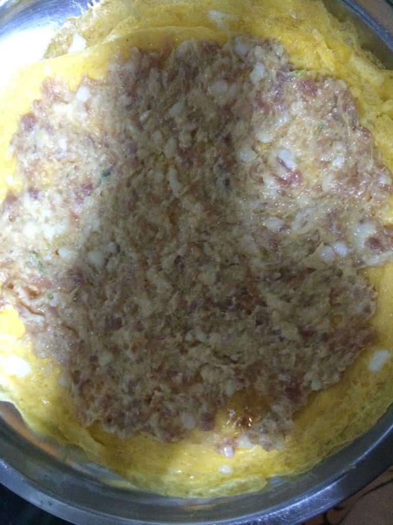 蛋香焖子,如图将摊好的鸡蛋饼铺平，均匀的抹上一层肉馅儿