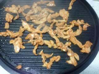 鸡肉卷饼,饼档热后刷一点油把鸡肉到在上面炒熟后盛出来备用。