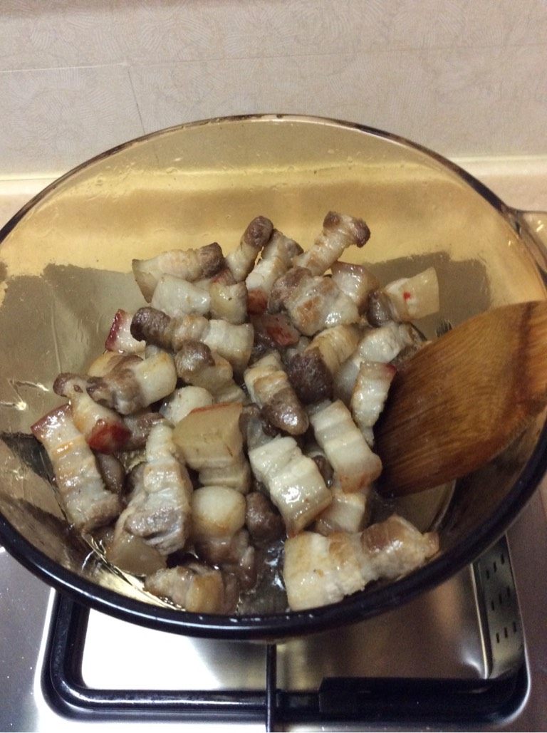 笋干菜烧肉,干锅上灶不加油，沥干水分的五花入热锅慢火炒至出油。