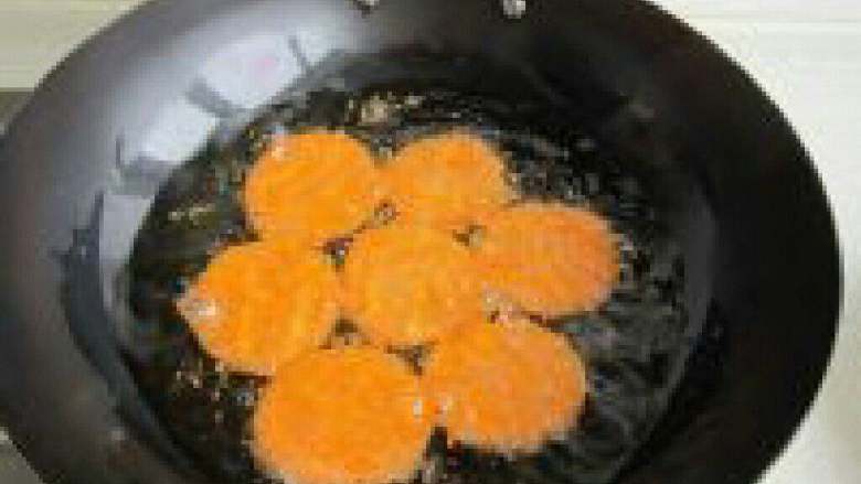 炸胡萝卜空心饼,锅里放油把胡萝卜饼放进炸。