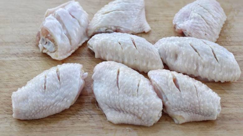 蒜香焖翅,将鸡翅放入清水中浸泡半小时左右，洗净后用厨房纸擦干表面多余水分，然后在鸡翅的正反面划几刀以方便入味。