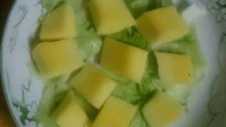芒果虾仁萨拉,芒果去皮去掉核切成块，盘子里放几块菜叶把切好的芒果放在上面。