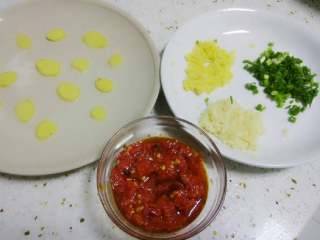 剁椒鱼头,准备好剁椒，葱姜蒜切细，再切一些姜片摆在盘子底部。