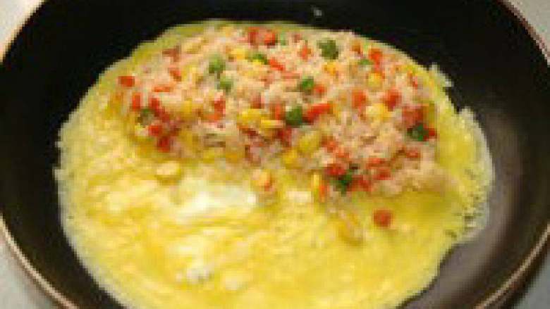 蛋包饭,待蛋液即将凝固时，在蛋皮一侧放入炒好的米饭
