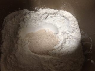 毛毛虫面包,如图分别将低筋粉、全麦粉、高筋粉加入面包桶，中间挖一个坑，加入干酵母后用面粉盖住；