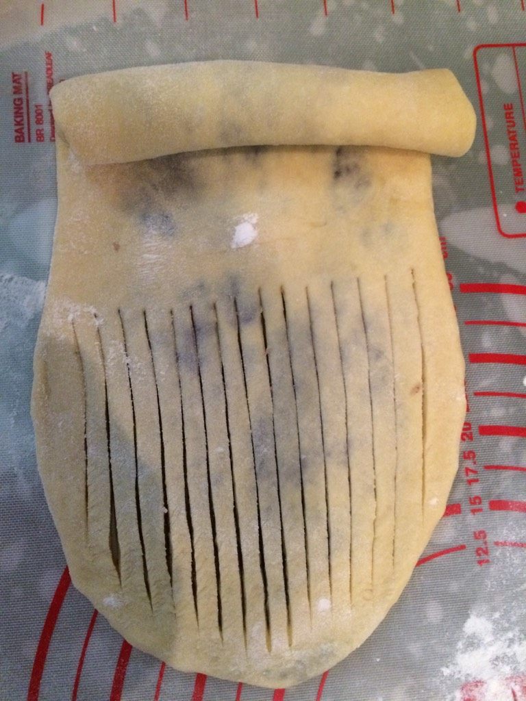 毛毛虫面包,如图从一头卷起约3分之2，剩下3分之1处用刀切成条状（收口处不要切断）；