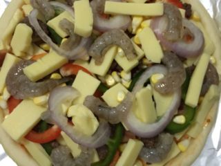大虾牛肉披萨,如图，在撒上厚厚的一层马苏里拉，然后在放入玉米粒、和鲜虾