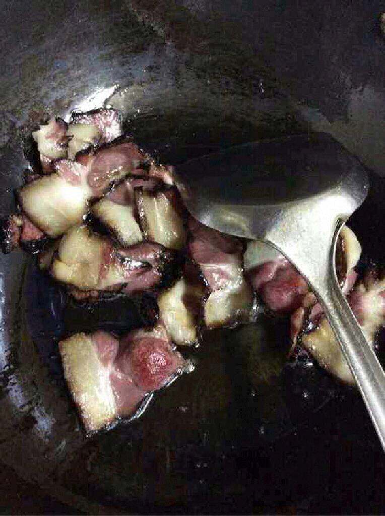 自创【蒜苔炒腊肉】,锅里放适量油把煮过的腊肉放进去炒出油。