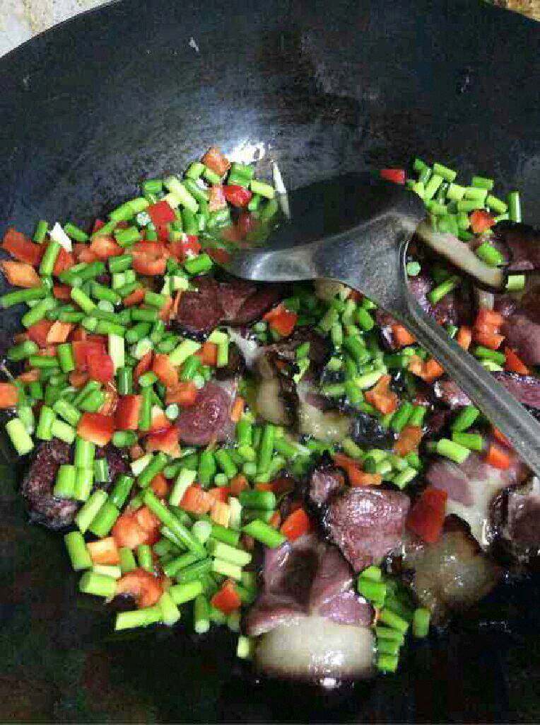 自创【蒜苔炒腊肉】,在倒进红辣椒翻炒，撒一点点盐在蒜苔和辣椒上，然后继续翻炒到熟后盛出。
