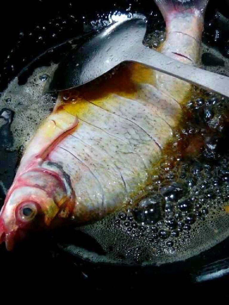 自创【干扁武昌鱼】,在把腌制好的鱼放进去炸。