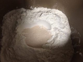 培根芝士面包,如图将低筋粉、全麦粉、高筋粉全部倒入面包桶，中间挖一坑，加入干酵母，然后用面粉将坑盖住；