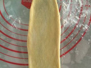 椰香豆沙卷面包,如图用擀面杖将面团擀成长圆形；