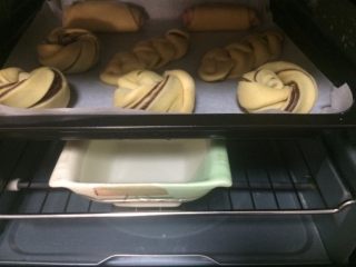 椰香豆沙卷面包,如图将烤盘放入烤箱中层，下层放一碗开水，烤箱启动发酵程序，温度40度，时间40-50分钟，发至2倍大；