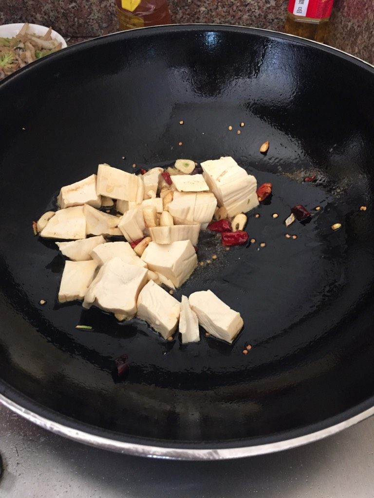 鱼子焖豆腐,锅里放油，加入大蒜、干辣椒豆腐入锅翻炒