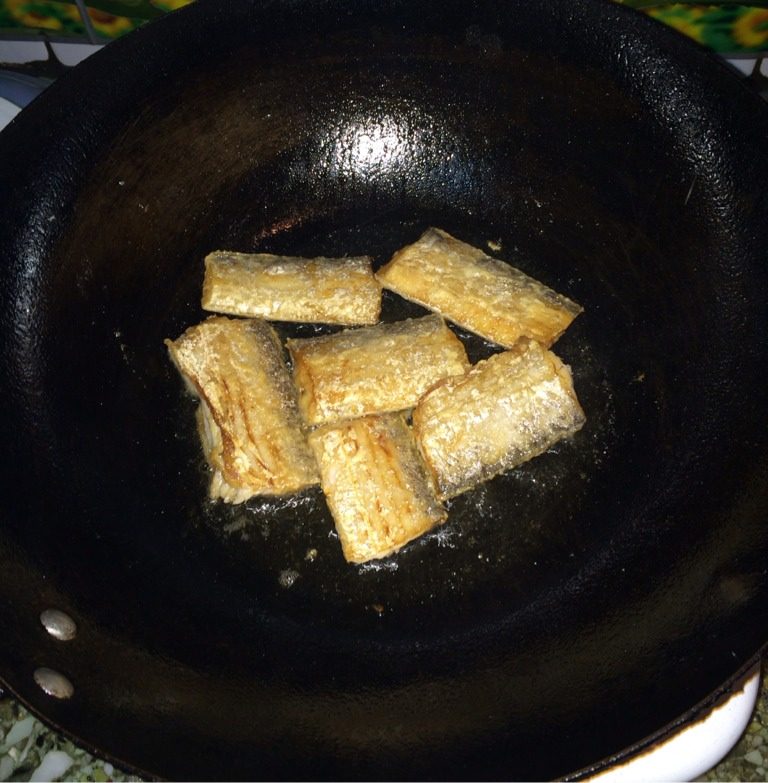 带鱼炖豆腐,油锅烧热，将鱼段两侧粘上面粉，再下油锅，煎至金黄