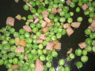 蒜香豌豆火腿,待豆粒受热涨圆时，加入火腿粒，翻炒，加入盐等调料