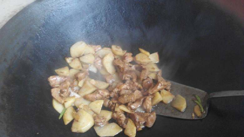 家常小炒肉,肉片炒至断生变色时放入土豆继续翻炒